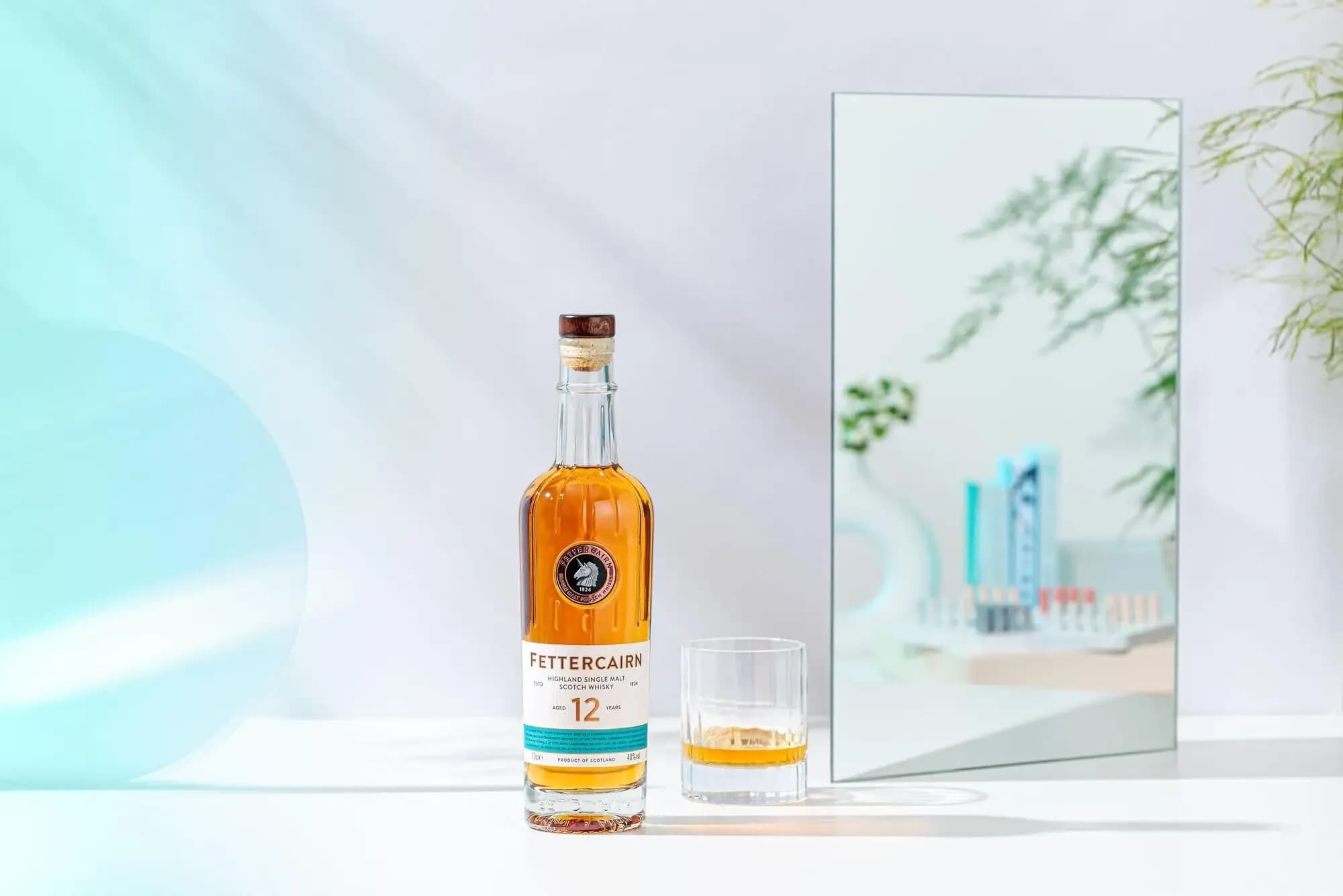 A Fettercairn 12-year-old single malt whisky bottle stands beside a filled glass.