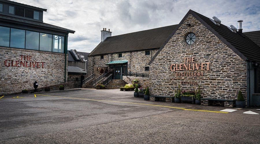 The Glenlivet Distillery's stone buildings with brand name displayed on their facades.