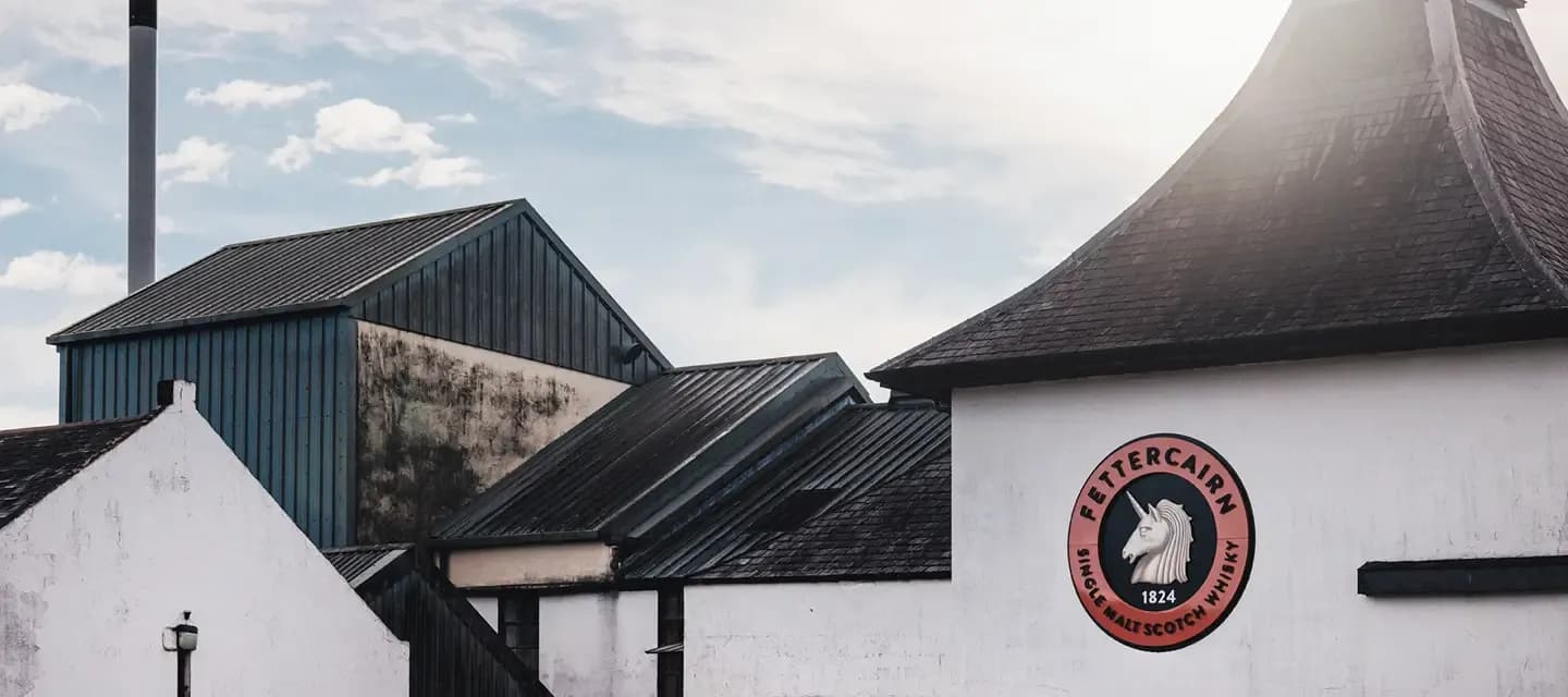 Exterior view of the Fettercairn Distillery with its distinctive white walls and dark roofs.