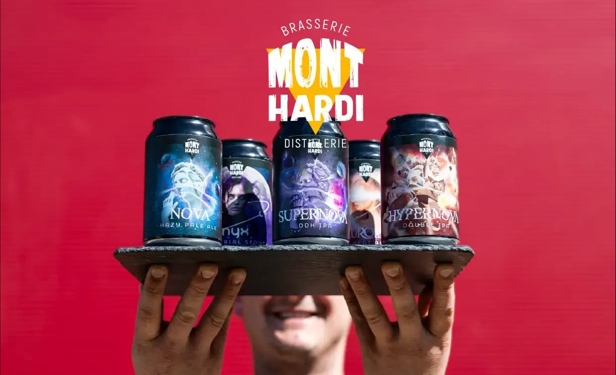 Smiling person holds a tray showcasing five different Brasserie Mont Hardi craft beer cans.